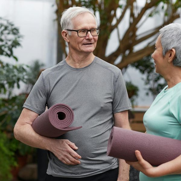 Group of diverse women smiling and holding yoga mats.